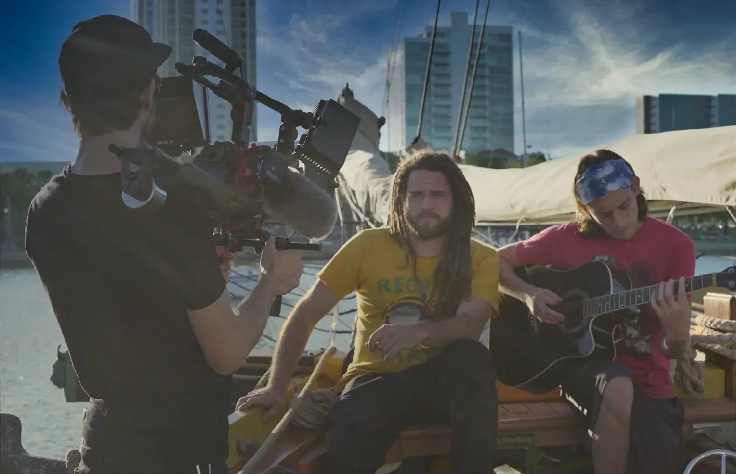 A videographer films a band performing on a boat in the harbor