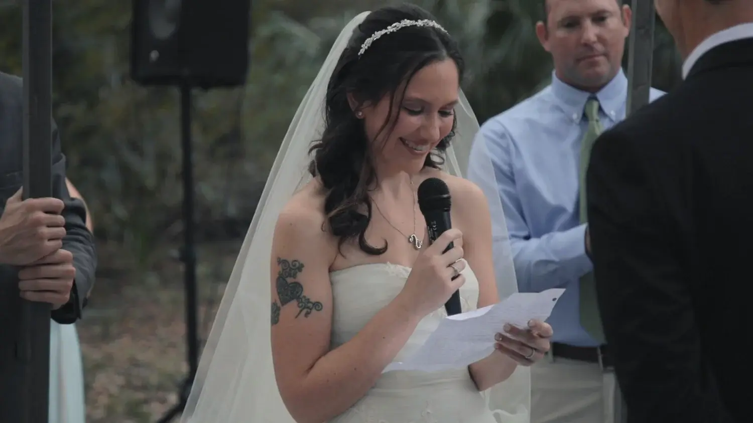 A bride speaks into a microphone at her wedding ceremony